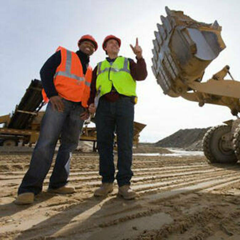 Two construction workers talking beside a CAT loader