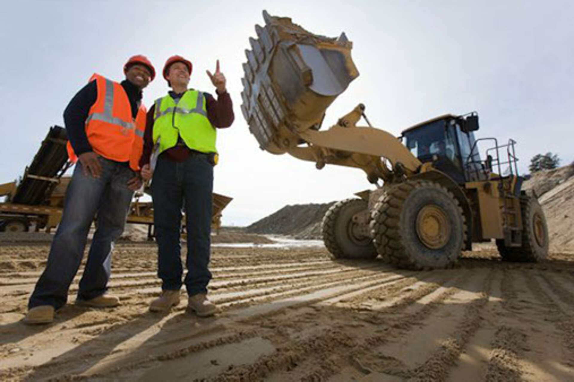 two construction workers standing in front of a CAT loader