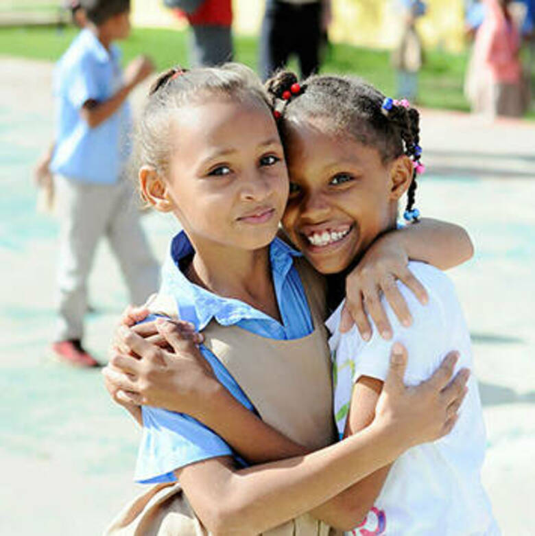 two young Dominican girls hugging as friends