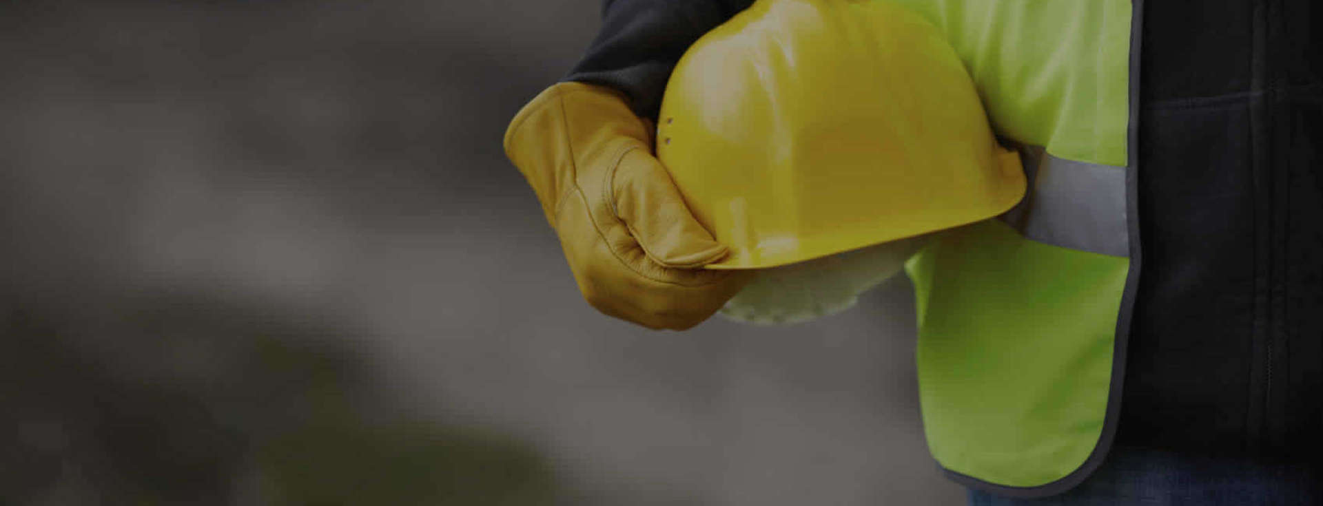construction worker holding a yellow hard-hat at their side.
