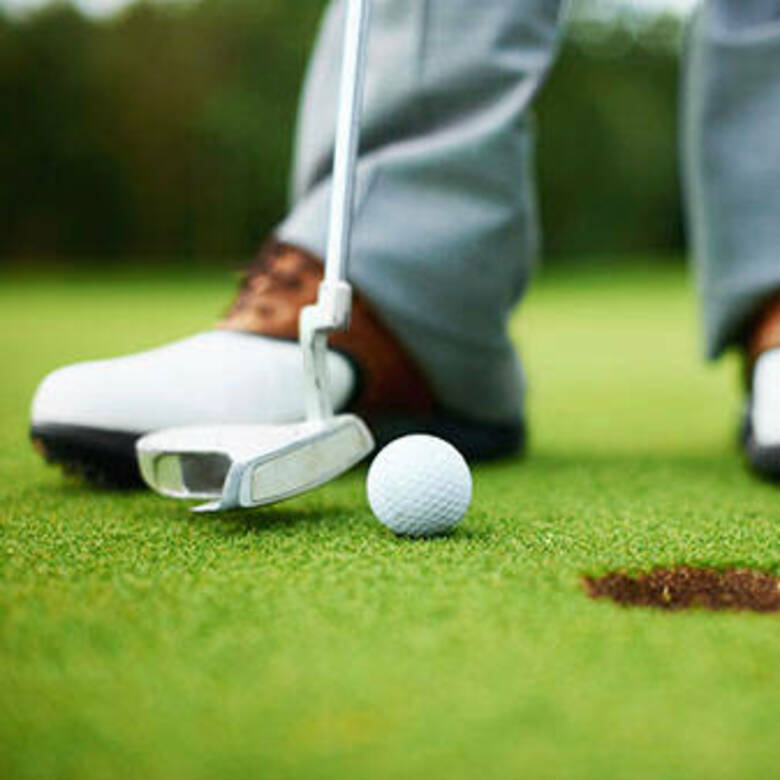 photo of the golfer's feet with the putter and ball